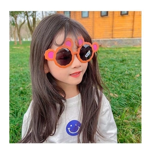 Detail showing a young girl wearing orange bear-ear sunglasses in an outdoor park