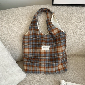 Detail of vintage plaid wool tote bag with textile texture on a cozy fabric background