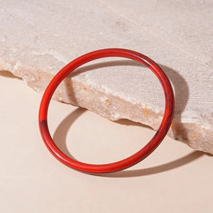 Détail d'un bracelet jonc en acrylique rouge aux couleurs acidulées et texture marbrée