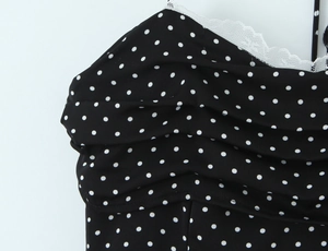 Detail of polka dot dress featuring pleated chest design and white lace trim at the neckline