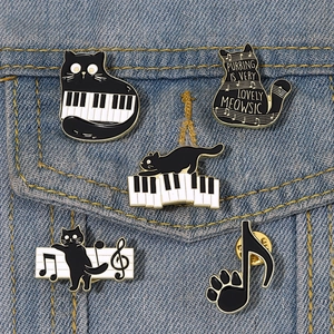 Detail of five cat and music enamel pins on a blue denim jacket pocket showing styling ideas