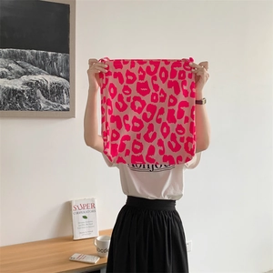 Close-up of pink leopard print canvas tote bag held by model in a cozy indoor setting