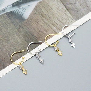 Detailed view of silver and gold plated earrings with zircon drop and rhombus charms