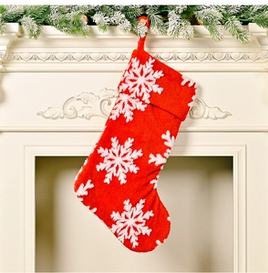 Detail of red plush Christmas stocking with white snowflakes hanging on a festive mantel