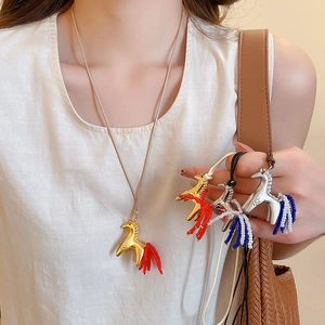 Detail of horse pendant necklace with colorful beaded tail on a gold chain