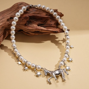 Detailed view of pearl necklace with silver pony pendant and hanging stars on wood