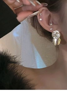 Close-up of a model wearing silver tassel sequin earrings and rhinestone ear studs