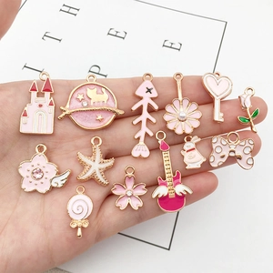 Set of 13 pink enamel and gold alloy charms featuring floral and celestial shapes