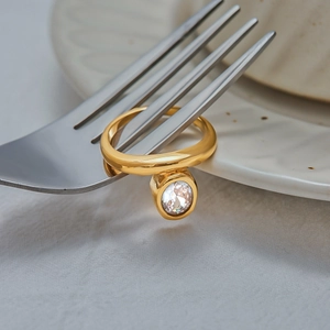 Creative close-up of an 18K gold stainless steel ring with zircon on silver fork tines