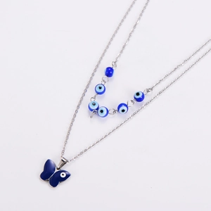 Close-up of double-layered silver necklace featuring blue evil eye beads and butterfly pendant