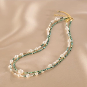 Close-up of double-layered necklace with natural pearls and turquoise on satin fabric