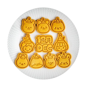 9-piece set of yellow mini cartoon animal cookie cutters on a textured white plate