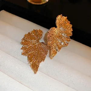 Golden leaf pattern earrings with detailed vein texture in a velvet jewelry box