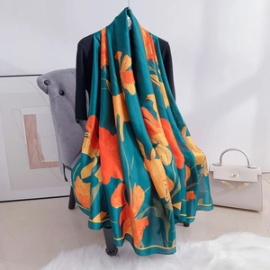 Detail of a large dark green silk scarf with vibrant orange and yellow floral patterns