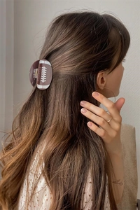Rear view of a model wearing the brown rugby-shaped hair claw clip on a half-up ponytail