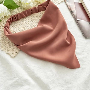Detail of dusty pink chiffon headscarf with elastic band on decorative white fabric