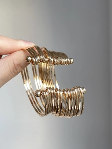 Detail of multi-layer gold metal cuff bracelet with industrial style ball bar fastener