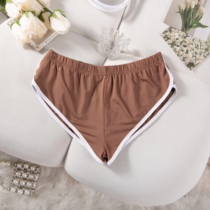 Detailansicht brauner Sport-Shorts mit weißer Paspelierung auf weichem Grund