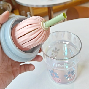 Gros plan du couvercle en silicone rose et paille verte sur un verre à fleurs