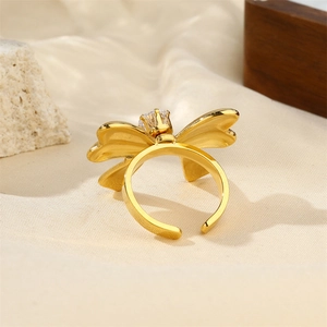 Detail of 18k gold-plated bow ring with sparkling zircons on a rustic fabric background