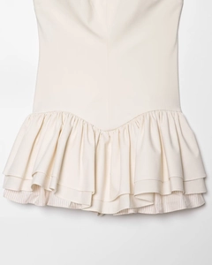 Detailed close-up of cream off-white pleated mini skirt with wavy hem and layered design