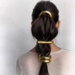 Close-up of golden curved and geometric metal hairpins on a woman's hair