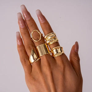 Detail of 5-piece gold geometric rings set showing polished finishes on female model hand
