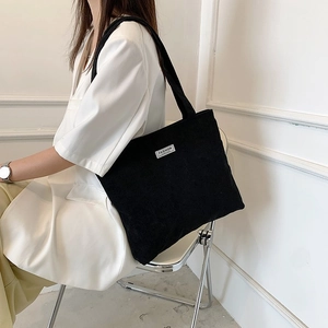 Detail showing black corduroy tote bag with Fashion label and long shoulder strap