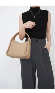 Minimalist beige leather pillow handbag held by model for professional commuter style