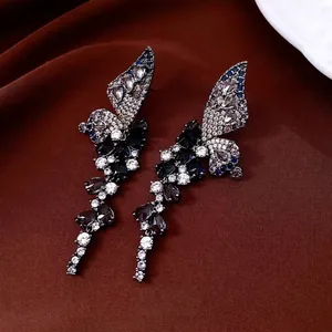 Elegant wing-shaped drop earrings with purple zircon tassels on dark velvet