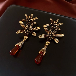 Detail of vintage gold flower earrings featuring amber resin teardrop pendants
