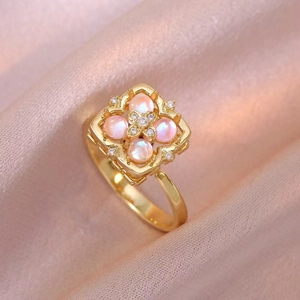 Golden flower ring with pink pearls and zircon diamonds on elegant pink silk background