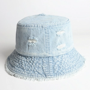 Detail of light blue distressed denim bucket hat with ripped holes and frayed edges