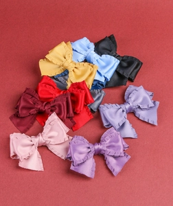 Gros plan de nœuds en ruban satiné à bords ondulés multicolores sur fond rouge texturé