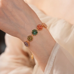 Macro view of gold-plated flower bracelet featuring colorful zircon stones on wrist