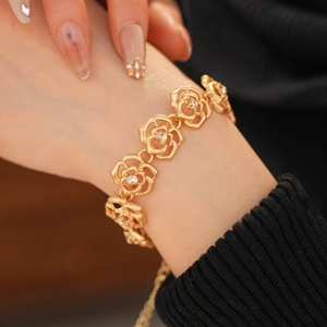 Close-up of gold rose hollow bracelet with rhinestones worn on a model wrist
