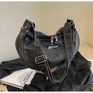 Detail of black denim crescent bag with double zipper and leather rivet accents