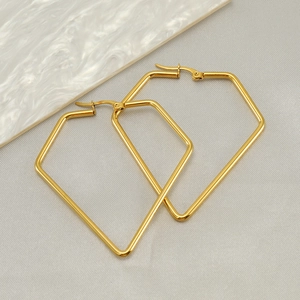Polished gold stainless steel elongated hexagonal geometric earrings on textured fabric