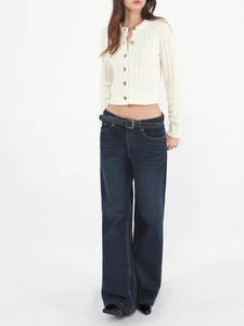 Detail of white cable knit cardigan paired with high-waist jeans and black belt