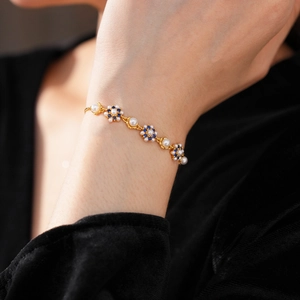 Detail view of vintage pearl and blue zircon flower bracelet on a black velvet sleeve