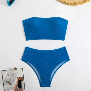 Flat lay of royal blue high-waisted bikini set with textured fabric and beach accessories