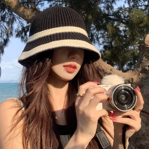 Knitted black and white striped sun hat bucket style for women in outdoor sunny beach setting