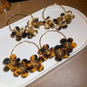 Detail shot of large gold-plated hoop earrings with leopard print fabric flower accents