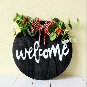 Black round wooden welcome door sign with eucalyptus leaves and red white striped bow