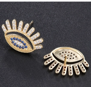 Macro view showing both sides of a gold evil eye pin earring with blue and clear zircons