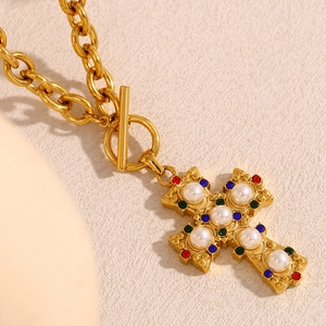 Vintage 18K gold plated cross necklace with colorful gemstones and pearls on a beige surface