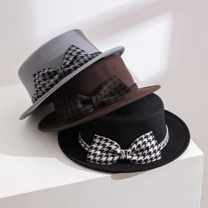 Gros plan de chapeaux en laine vintage avec nœud pied-de-poule en trois couleurs.