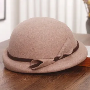 Elegant wool beret hat with a brown ribbon bow on a wooden surface in warm indoor light