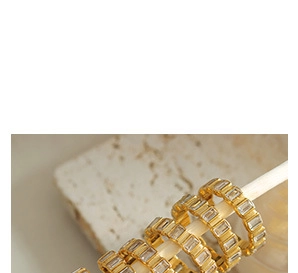 Macro detail of gold plated rings featuring channel-set rectangular zircon stones