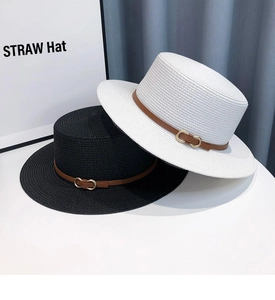 Close-up of flat straw hats with brown leather bands and gold buckles in black and white